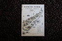 North Fork Coffee Trail map card and Trail Card resting on coffee beans